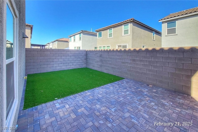 view of yard featuring a residential view, a patio area, and a fenced backyard