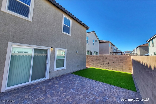 back of property featuring a patio, a tile roof, a residential view, fence, and stucco siding