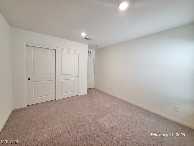 unfurnished bedroom with carpet floors, baseboards, visible vents, and a closet