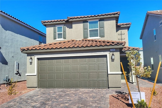 mediterranean / spanish house featuring a garage, decorative driveway, and stucco siding