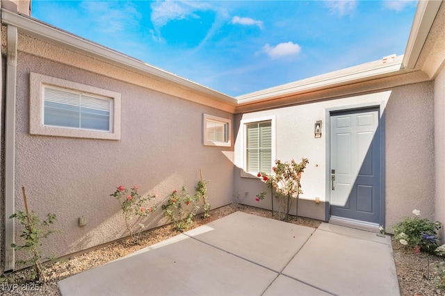 view of exterior entry with a patio area and stucco siding