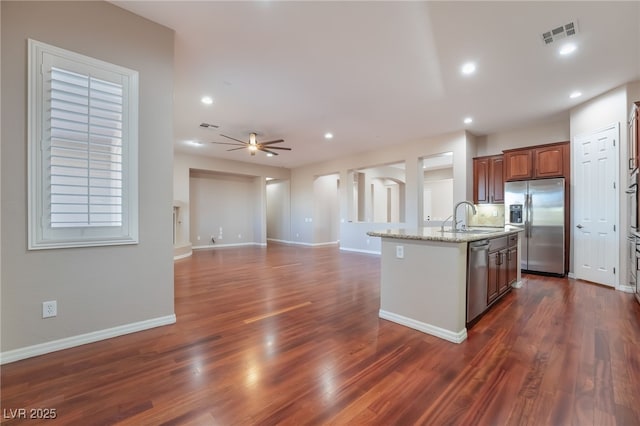 kitchen with visible vents, appliances with stainless steel finishes, light stone counters, dark wood-type flooring, and recessed lighting