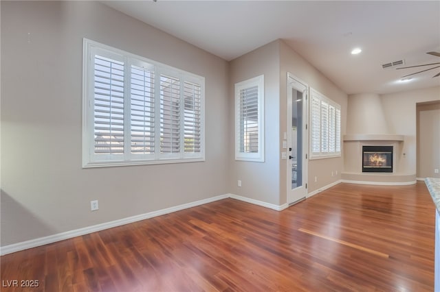 unfurnished living room with baseboards, a fireplace, visible vents, and wood finished floors