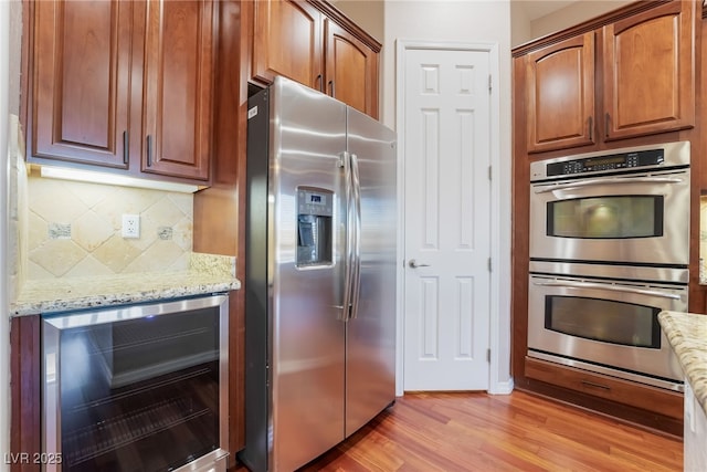 kitchen featuring light stone countertops, tasteful backsplash, wine cooler, and stainless steel appliances