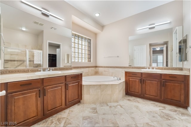 bathroom with a stall shower, a garden tub, a sink, and visible vents