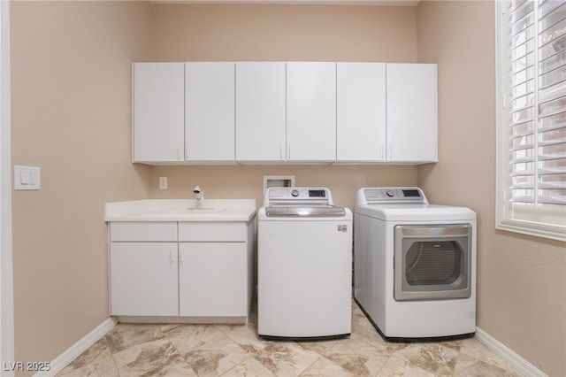 laundry area featuring washing machine and dryer, a sink, cabinet space, and baseboards