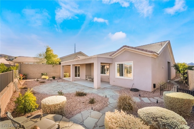 rear view of property featuring a fenced backyard, a patio, a tiled roof, and stucco siding