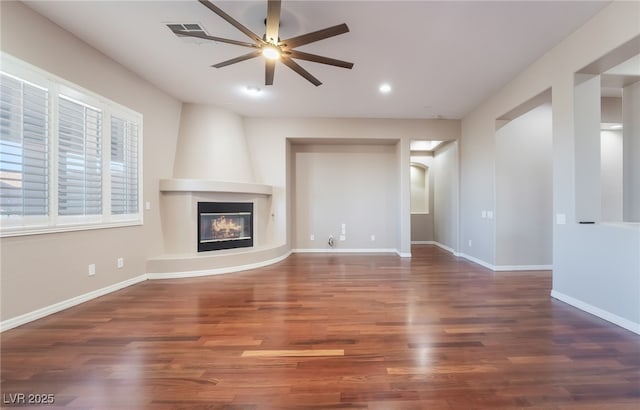 unfurnished living room featuring ceiling fan, a fireplace, wood finished floors, and baseboards