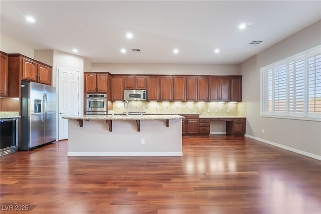 kitchen with built in desk, stainless steel appliances, tasteful backsplash, visible vents, and a sink