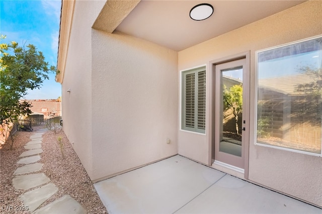 doorway to property with a patio area, fence, and stucco siding