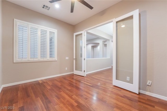 empty room featuring visible vents, ceiling fan, baseboards, and wood finished floors