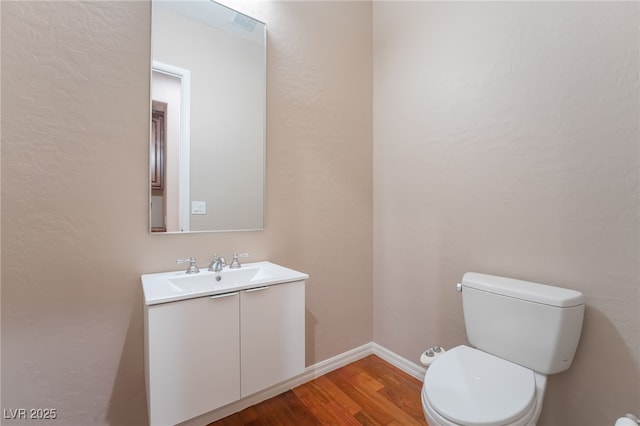 bathroom featuring vanity, wood finished floors, toilet, and baseboards