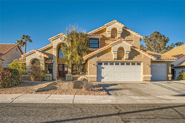 mediterranean / spanish-style home with a garage, concrete driveway, a tile roof, and stucco siding