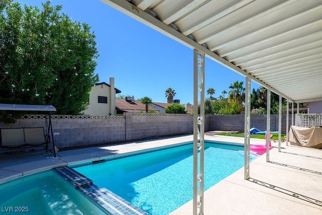 view of swimming pool featuring a fenced backyard, a pool with connected hot tub, and a patio