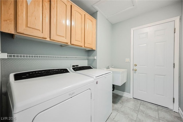 washroom with cabinet space, attic access, washing machine and dryer, a sink, and baseboards