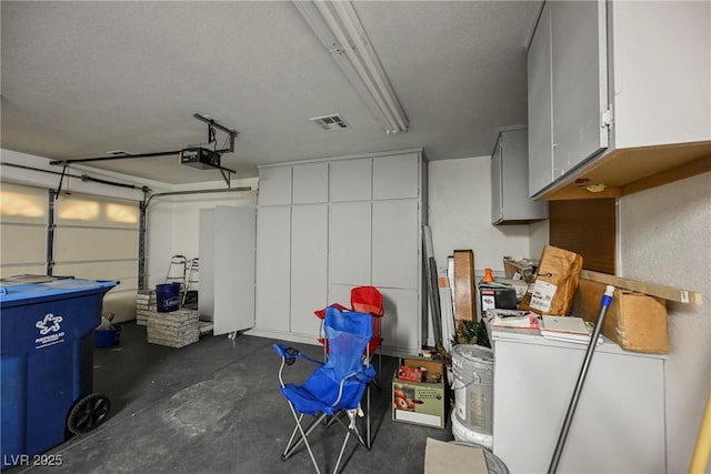 garage with a garage door opener, visible vents, and fridge