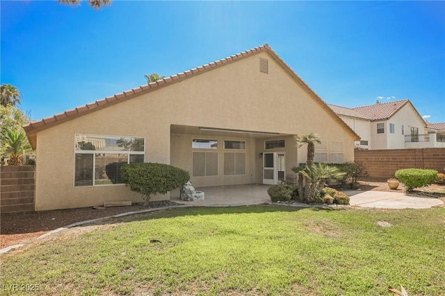 rear view of property featuring a lawn, a patio area, fence, and stucco siding