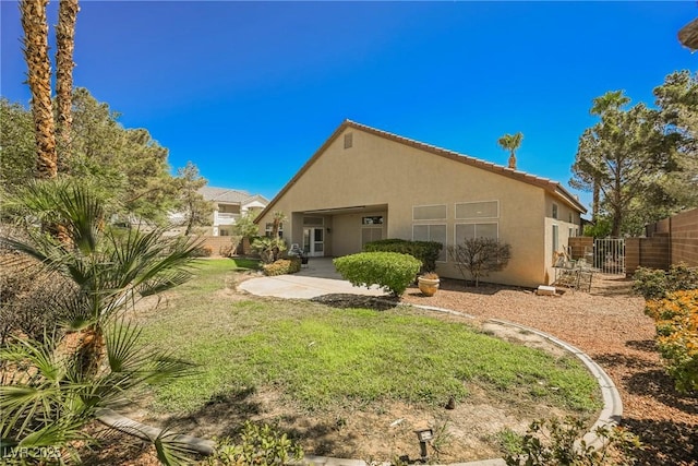 back of house with a patio area, a yard, fence, and stucco siding