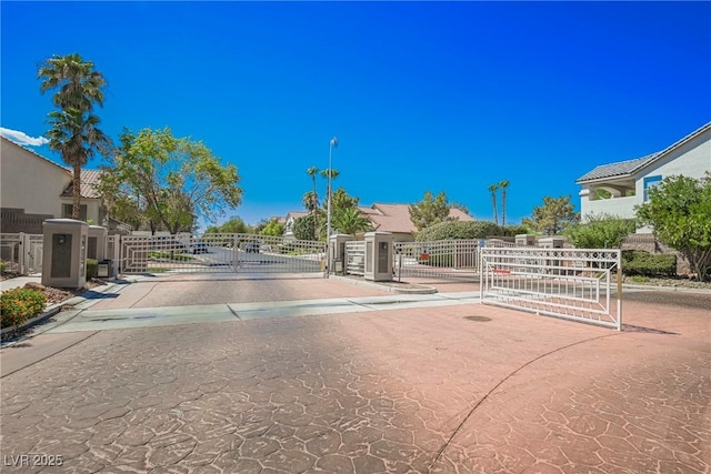 view of street with street lighting, a gate, curbs, and a gated entry