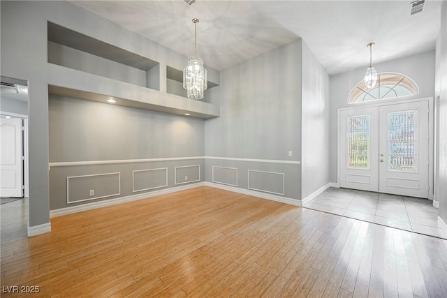 unfurnished dining area featuring light wood-style floors, visible vents, a decorative wall, and an inviting chandelier