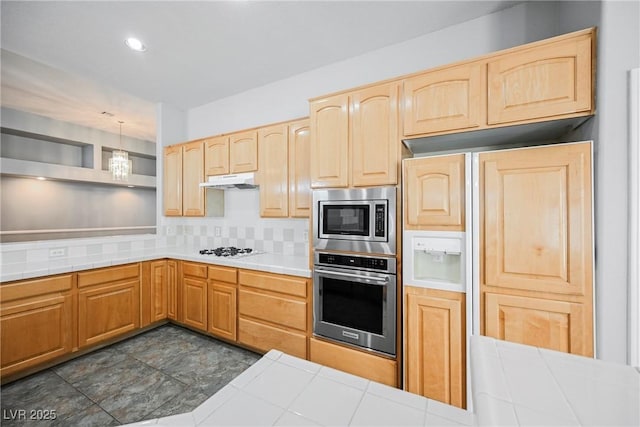 kitchen featuring appliances with stainless steel finishes, pendant lighting, tile countertops, and under cabinet range hood