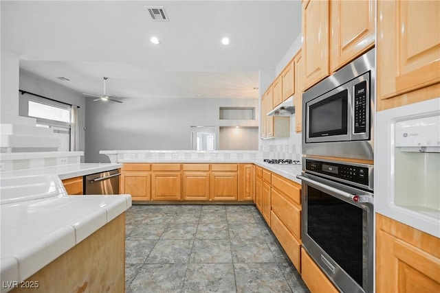 kitchen featuring stainless steel appliances, visible vents, light brown cabinets, a peninsula, and under cabinet range hood