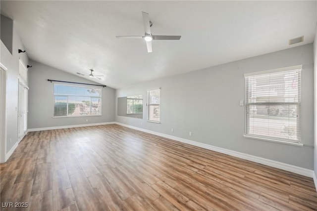 empty room featuring baseboards, visible vents, a ceiling fan, light wood-style flooring, and vaulted ceiling