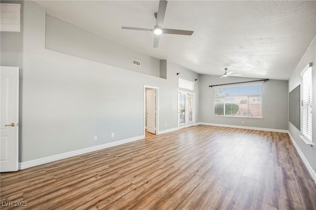 interior space featuring baseboards, visible vents, vaulted ceiling, a textured ceiling, and light wood-type flooring