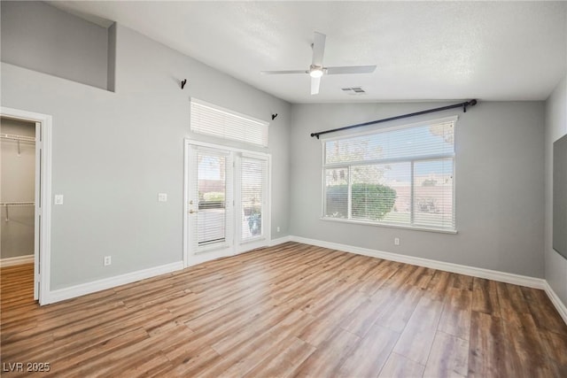 spare room with visible vents, vaulted ceiling, baseboards, and wood finished floors