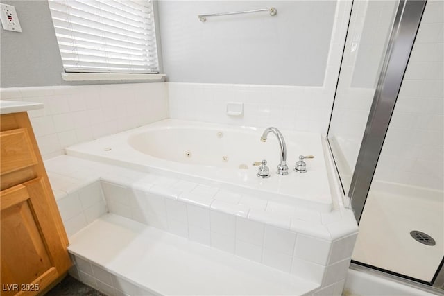 full bath featuring a jetted tub, vanity, and a stall shower