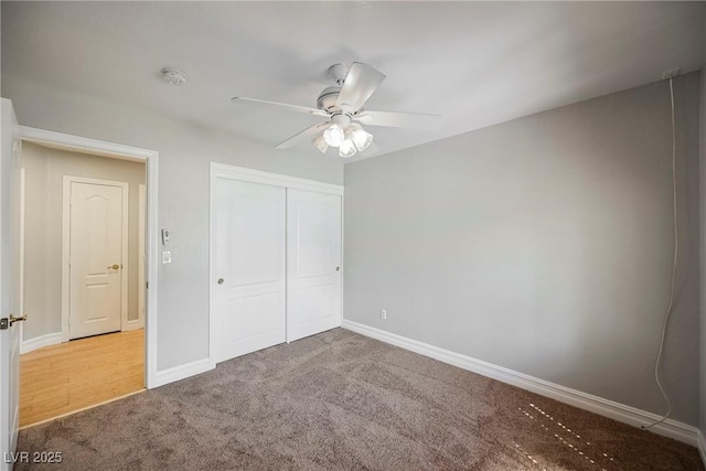 unfurnished bedroom with ceiling fan, a closet, baseboards, and carpet flooring