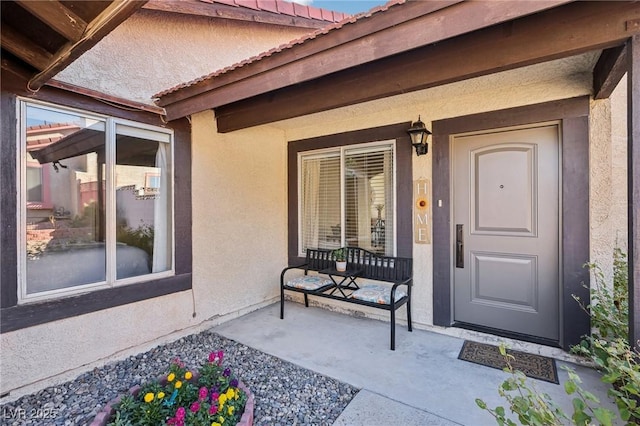 entrance to property with a porch and stucco siding