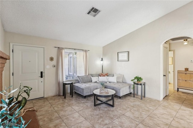 living room featuring arched walkways, visible vents, vaulted ceiling, and light tile patterned flooring