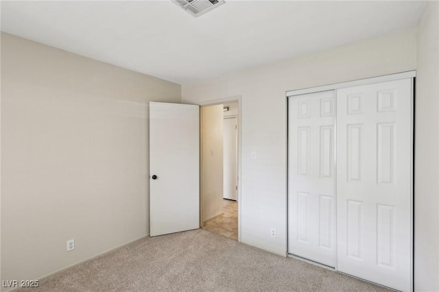 unfurnished bedroom with a closet, visible vents, and light colored carpet