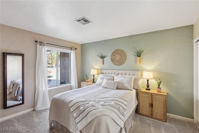 bedroom with baseboards, a textured wall, and light colored carpet