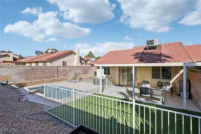 rear view of property featuring a lawn, a patio area, and a fenced backyard