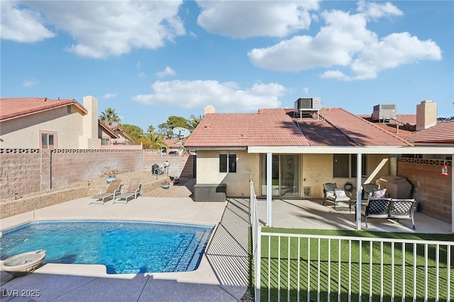 rear view of property featuring a patio, stucco siding, a lawn, a fenced backyard, and a tiled roof