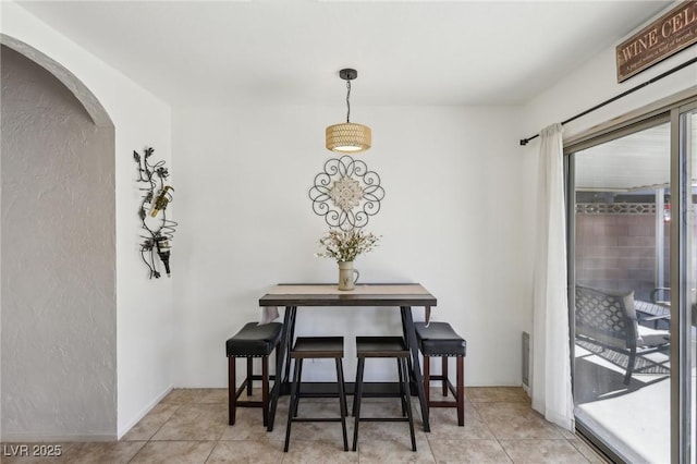 dining room with arched walkways and light tile patterned floors