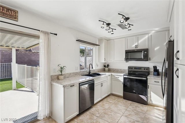 kitchen featuring light tile patterned floors, white cabinets, light stone counters, stainless steel appliances, and a sink