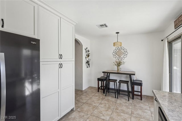 dining space featuring arched walkways, light tile patterned flooring, and visible vents