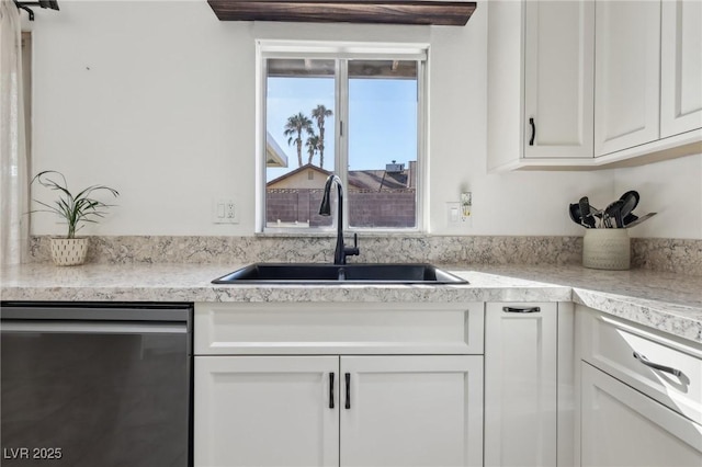 kitchen with a sink, white cabinetry, light countertops, and stainless steel dishwasher