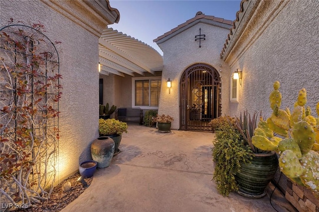 doorway to property featuring a pergola and stucco siding