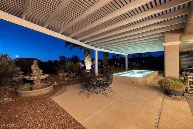 patio at twilight with outdoor dining space and an outdoor hot tub