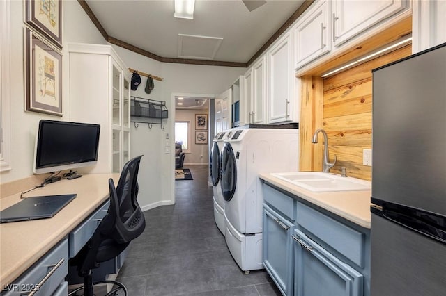 clothes washing area with washing machine and dryer, attic access, and a sink