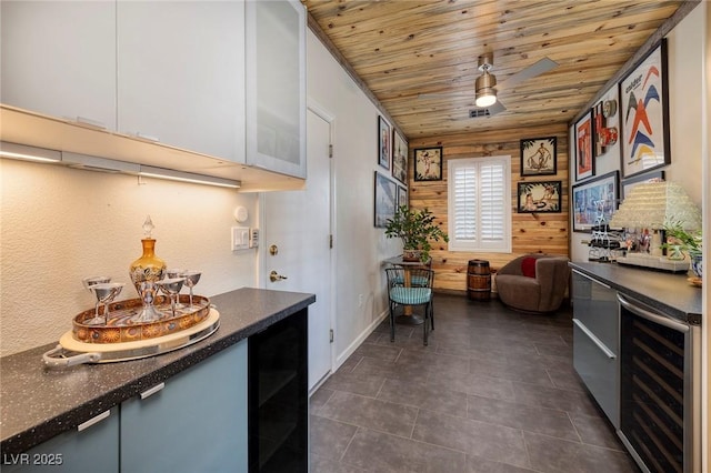 kitchen with dark countertops, wooden ceiling, beverage cooler, and a ceiling fan