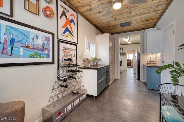 interior space featuring lofted ceiling, wood ceiling, visible vents, and dark tile patterned flooring