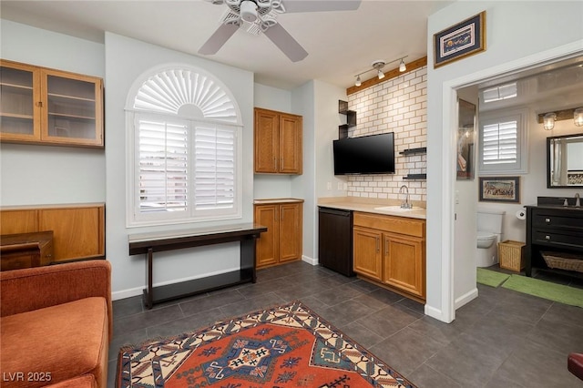 kitchen with a sink, black dishwasher, light countertops, brown cabinets, and glass insert cabinets