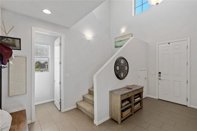 foyer with a healthy amount of sunlight, baseboards, and stairs