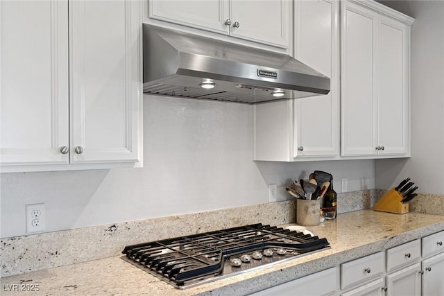 kitchen with stainless steel gas cooktop, light stone counters, white cabinetry, and under cabinet range hood