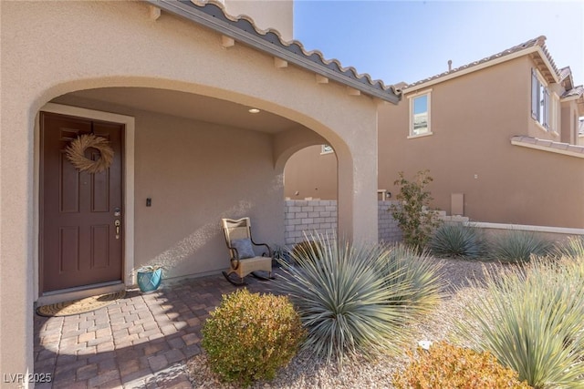 doorway to property featuring a tile roof and stucco siding